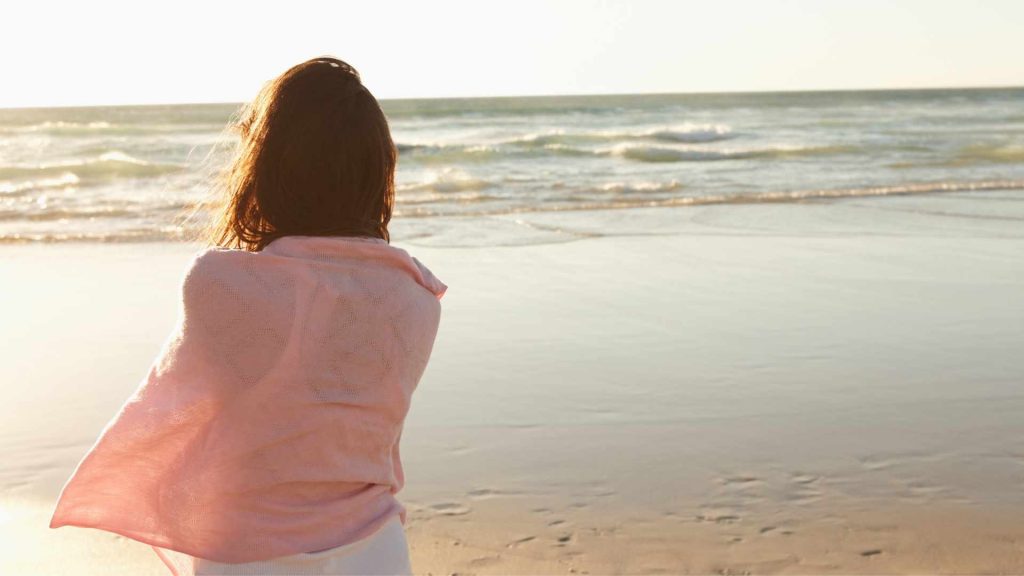 Woman standing with her back to camera looking at the ocean. Moving, a new job, graduation, marriage, divorce, retirement, empty nesters: men and women dealing with all of these major life transitions can benefit from Christian therapy for life transitions in Oregon here.