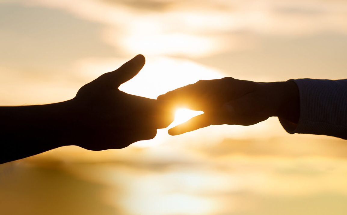 Image of two hands connecting in front of a bright light. Christian counselors in Portland, Oregon can help with worry. Start stress counseling in Clackamas, OR.