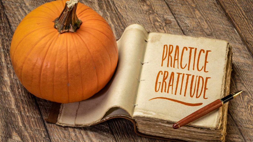 Practice Gratitude | Clackamas, OR Christian Counseling Pumpkin and Journal with "Practice Gratitude" with pen on wooden table. Consider working with a Christian counselor in Clackamas, OR for faith-based therapy online in Oregon.